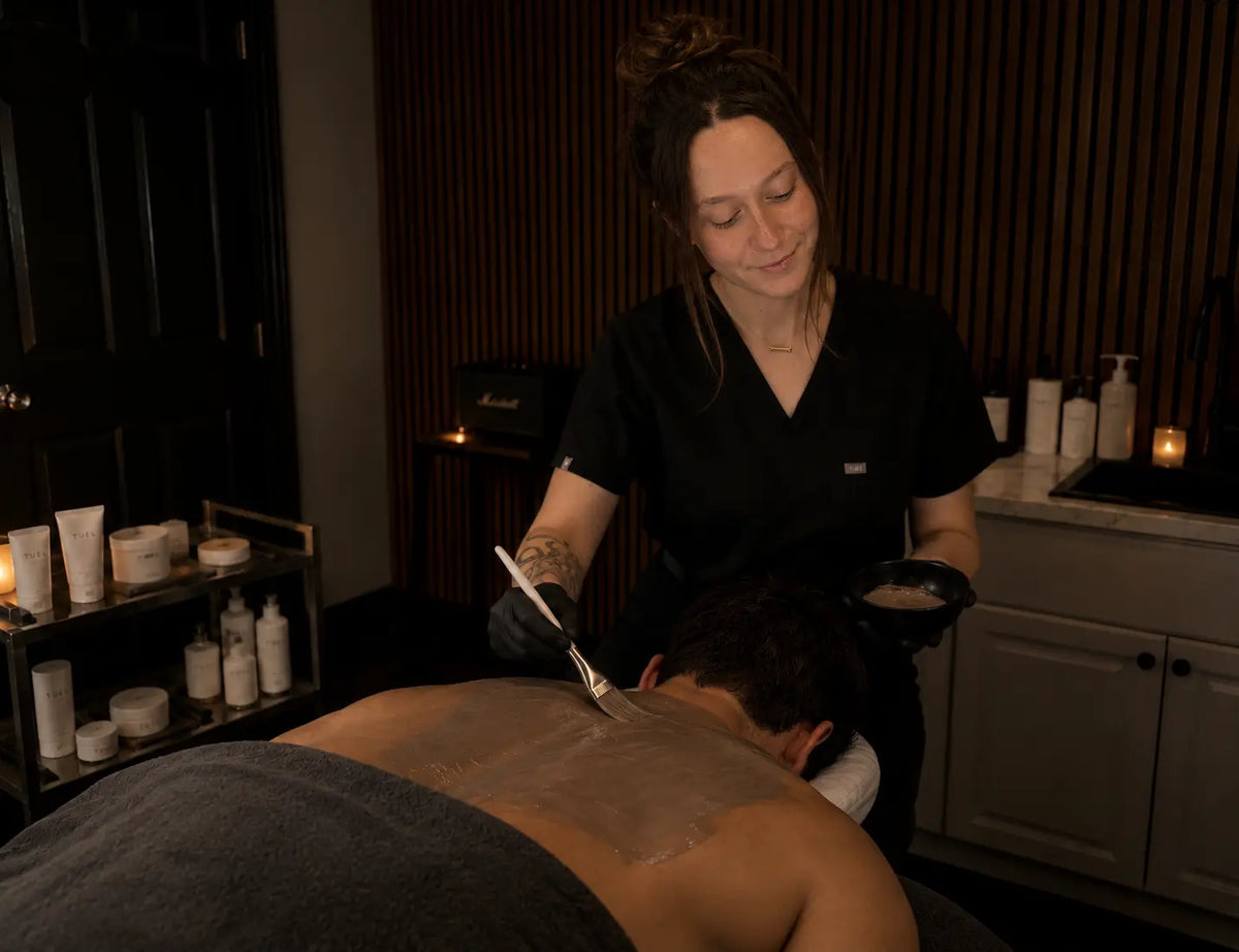 Esthetician at Menscape applying a mask during a back facial